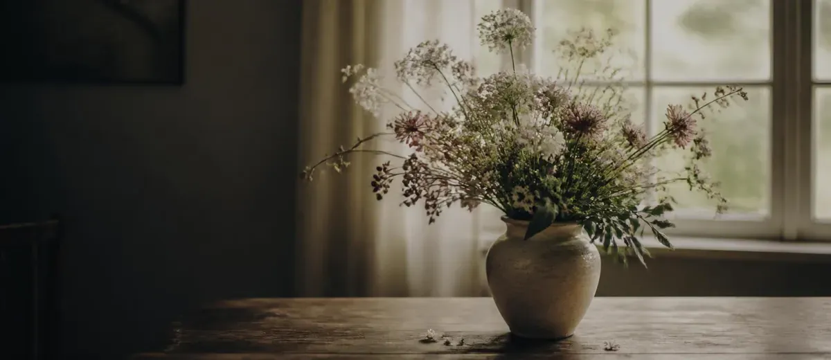 Arranjo de flores do campo em vaso de cerâmica diante de uma janela